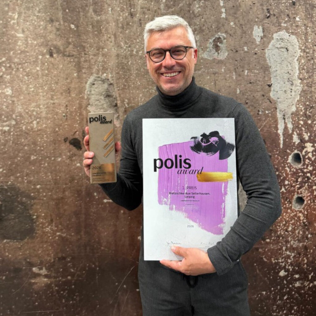 Robert Storch hält den Polis Award 2026 als 1. Preis in der Hand und präsentiert ein lila Urkundenplakat vor gesprenkeltem Hintergrund.