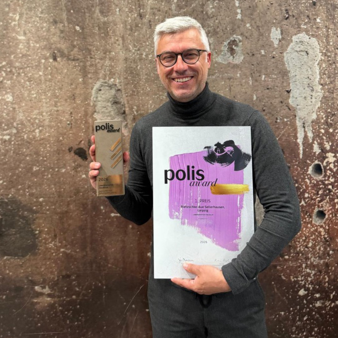 Robert Storch hält den Polis Award 2026 als 1. Preis in der Hand und präsentiert ein lila Urkundenplakat vor gesprenkeltem Hintergrund.